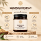 Swarnalaya Ubtan jar on a wooden surface with decorative leaves; highlights Ayurvedic features and benefits.